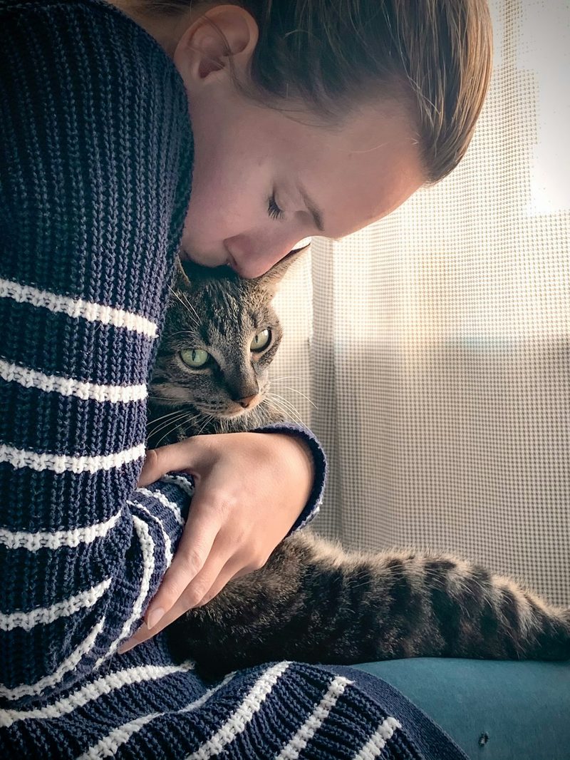 Woman cuddling a tabby cat on her lap